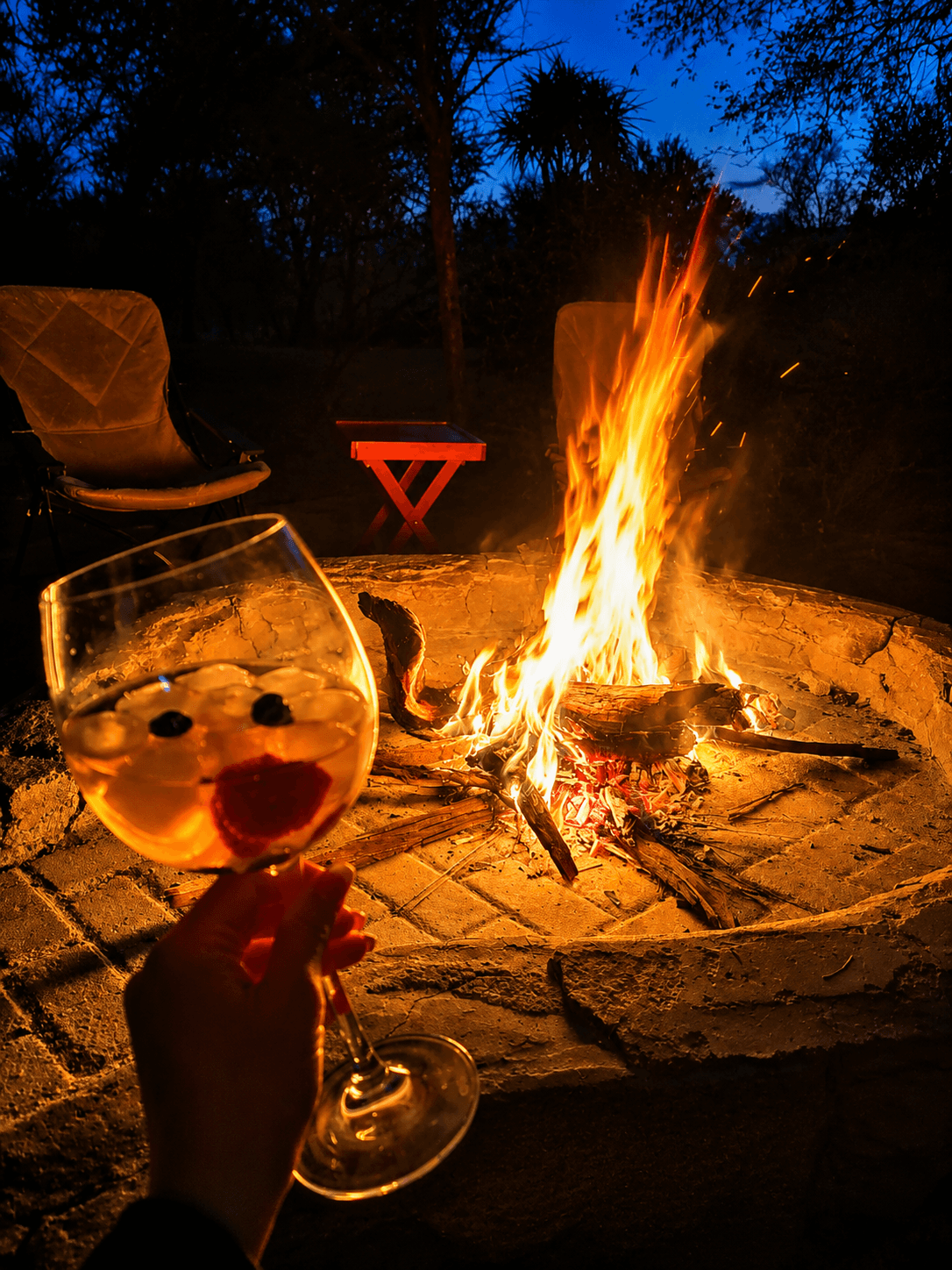 A sundowner gin held beside the firepit at dusk at Bougasvlei Safaris