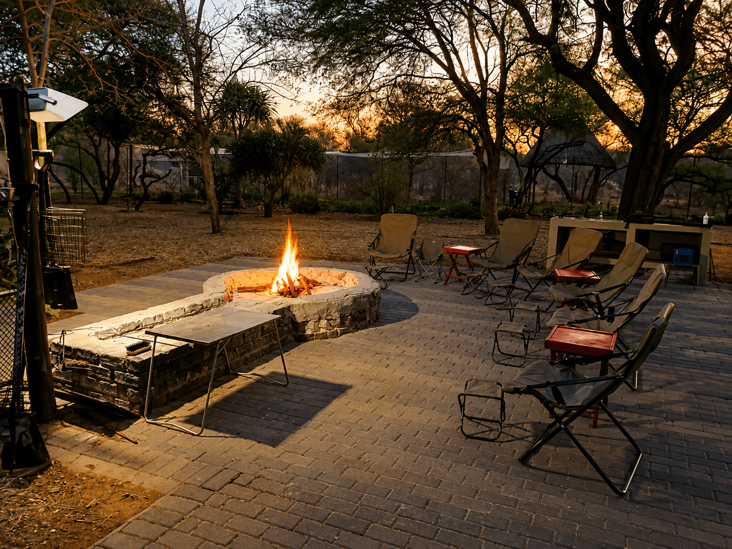 Boma and firepit glowing at sunset on the lodge patio at Bougasvlei Safaris