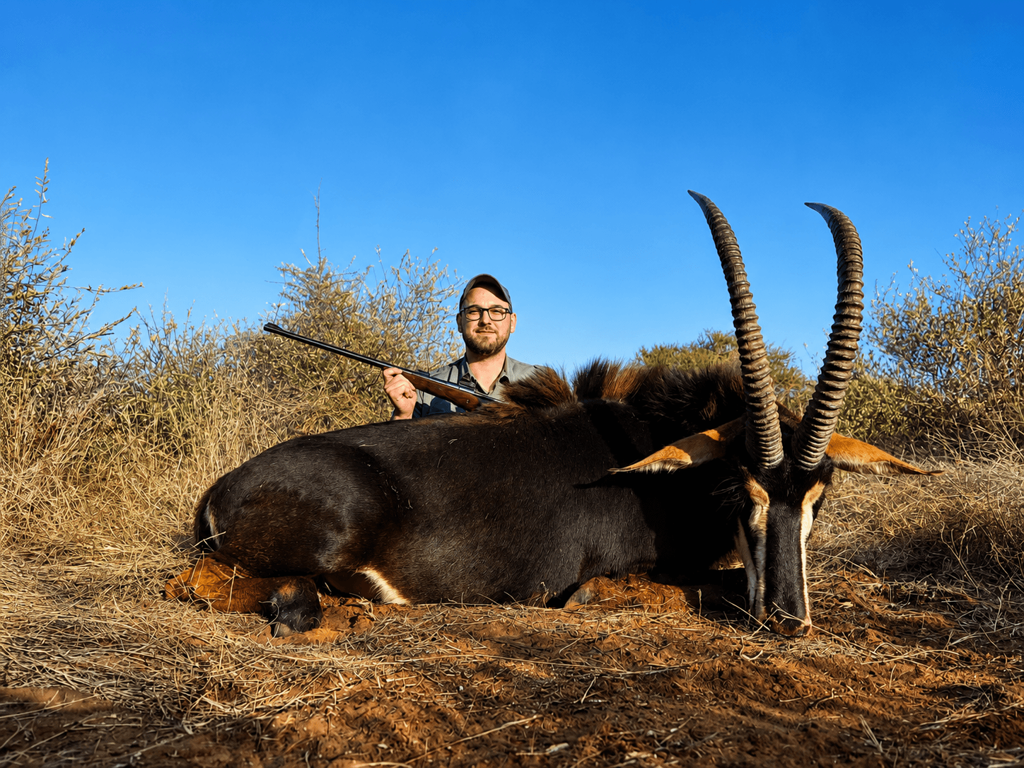 Hunter with a sable trophy and rifle after a fair-chase safari at Bougasvlei Safaris